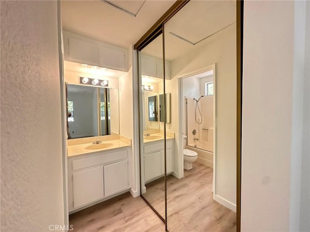 full bath with toilet,  shower combination, wood finished floors, and vanity