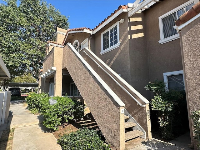 view of side of home with stucco siding and a tiled roof