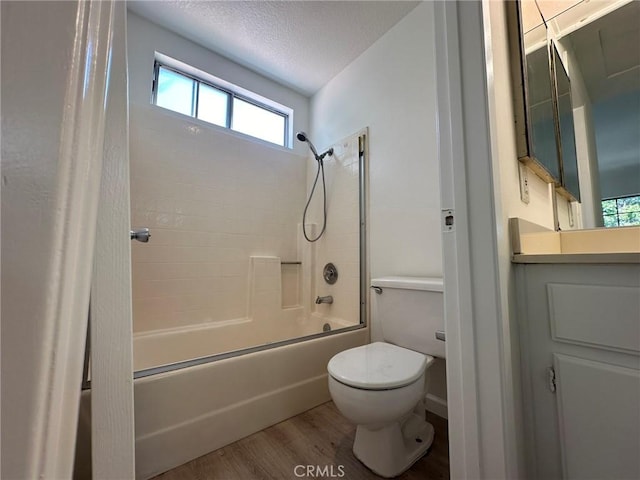 bathroom with washtub / shower combination, toilet, vanity, wood finished floors, and a textured ceiling