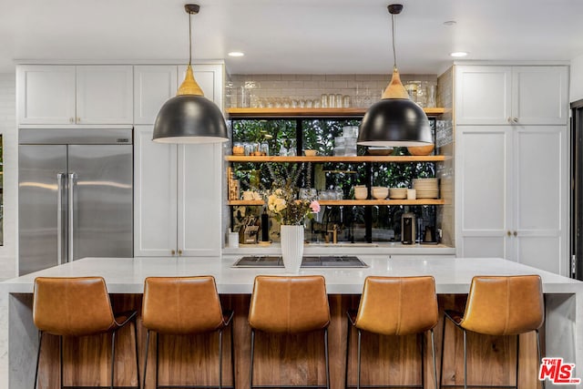 kitchen featuring decorative light fixtures, black electric stovetop, and white cabinetry