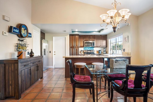 kitchen featuring light tile patterned floors, tasteful backsplash, hanging light fixtures, a chandelier, and appliances with stainless steel finishes