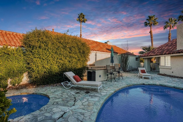 pool at dusk featuring a patio