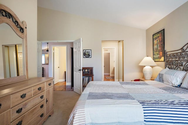 carpeted bedroom with ensuite bath and vaulted ceiling