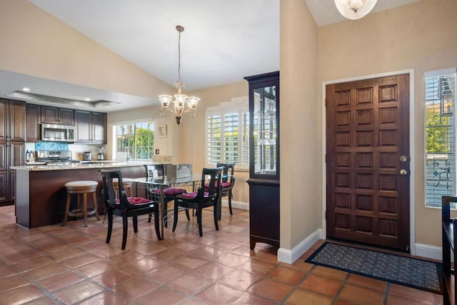 tiled dining room with vaulted ceiling and a notable chandelier