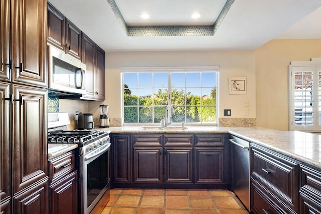 kitchen featuring stainless steel appliances, sink, a tray ceiling, and kitchen peninsula