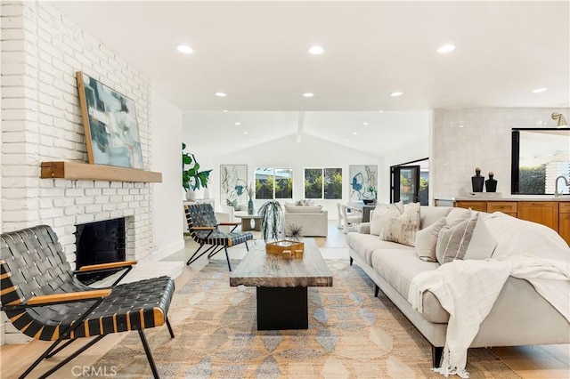 living room featuring sink, a brick fireplace, and vaulted ceiling with beams