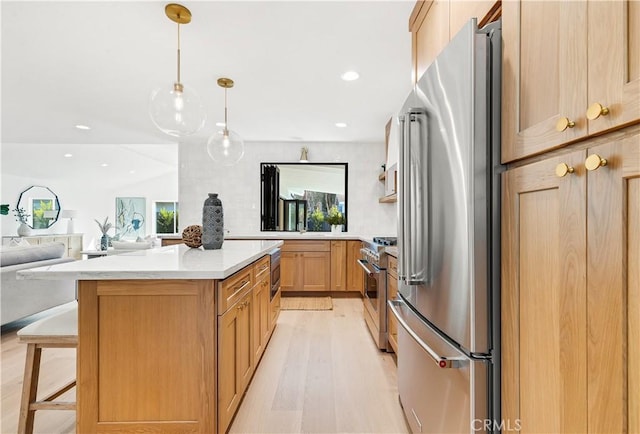 kitchen with light hardwood / wood-style flooring, premium appliances, decorative light fixtures, a breakfast bar, and light brown cabinets