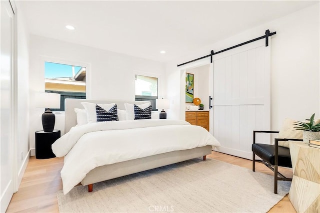 bedroom featuring light hardwood / wood-style floors and a barn door