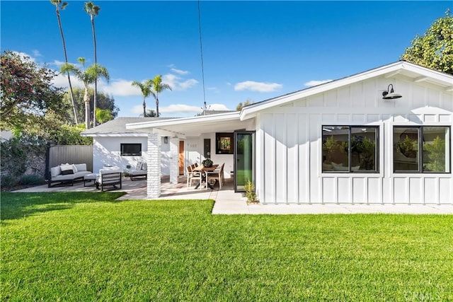 back of property with a patio area, a yard, and an outdoor living space