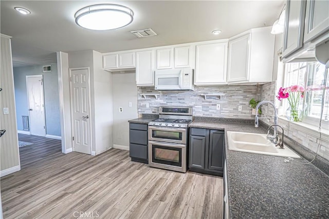 kitchen with light wood-type flooring, double oven range, decorative backsplash, sink, and white cabinetry