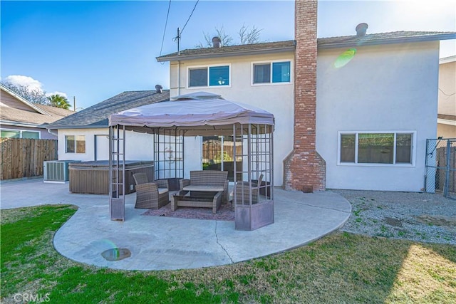 rear view of house with an outdoor hangout area, a patio, central AC, a hot tub, and a gazebo