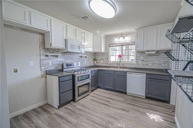 kitchen with white appliances, white cabinets, gray cabinets, and sink