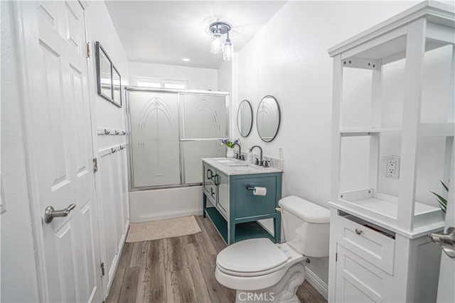 full bathroom with toilet, bath / shower combo with glass door, vanity, and hardwood / wood-style floors