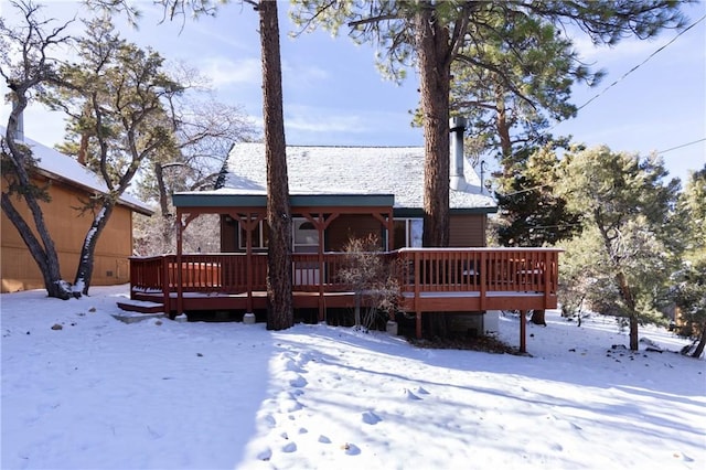 snow covered rear of property with a wooden deck