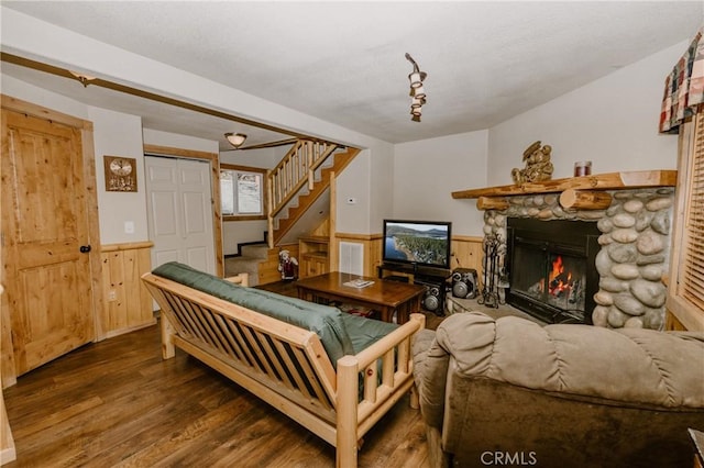 living room with wood walls, dark hardwood / wood-style floors, and a stone fireplace