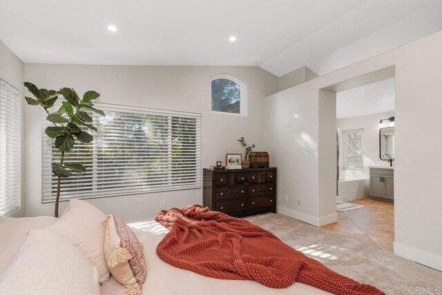 tiled bedroom featuring lofted ceiling and connected bathroom