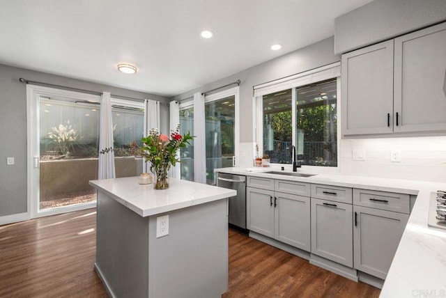 kitchen featuring a kitchen island, light stone countertops, dishwasher, and sink