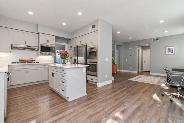 kitchen featuring white cabinets, appliances with stainless steel finishes, light hardwood / wood-style floors, and backsplash