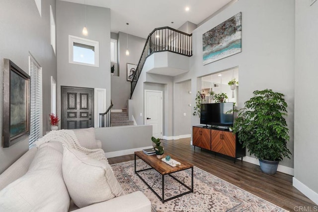 living room with a high ceiling and dark wood-type flooring