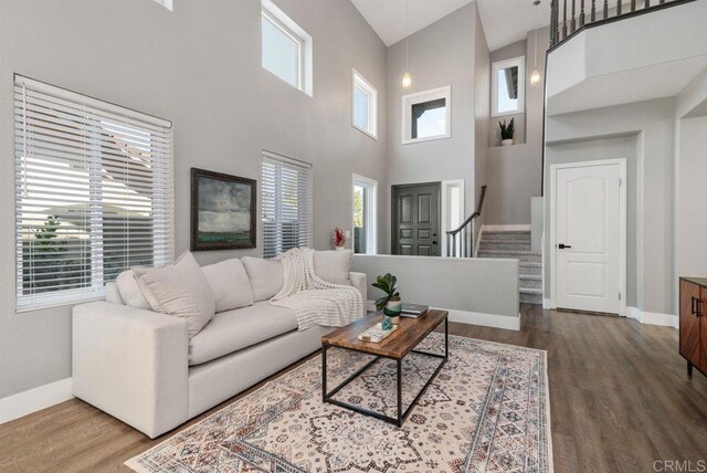 living room with a towering ceiling, wood-type flooring, and a wealth of natural light