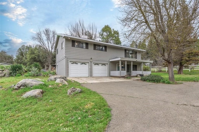 front of property with a front yard, covered porch, and a garage