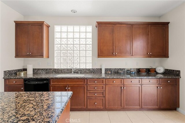 kitchen with light tile patterned floors, dishwasher, sink, and dark stone counters