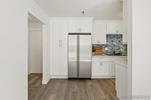 kitchen featuring white cabinets, built in refrigerator, tasteful backsplash, and sink