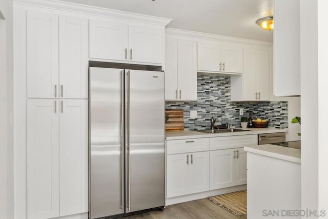 kitchen featuring sink, high quality fridge, tasteful backsplash, and white cabinetry