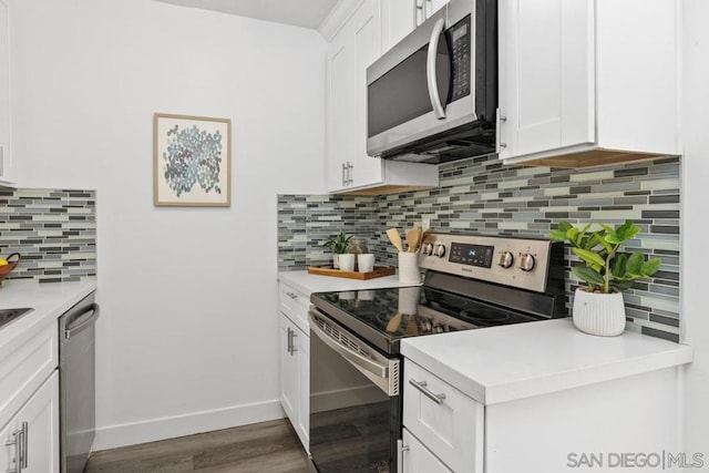 kitchen featuring appliances with stainless steel finishes, white cabinetry, dark hardwood / wood-style floors, and decorative backsplash