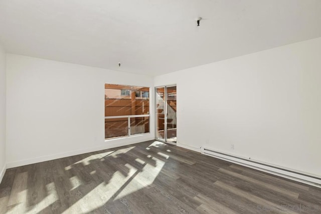 empty room with dark hardwood / wood-style flooring and a baseboard heating unit