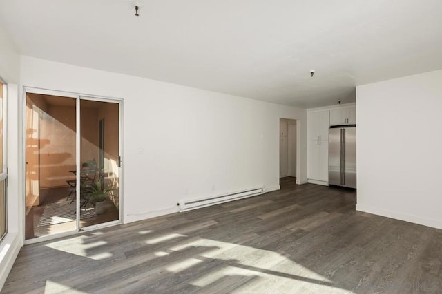 spare room featuring dark wood-type flooring and a baseboard heating unit