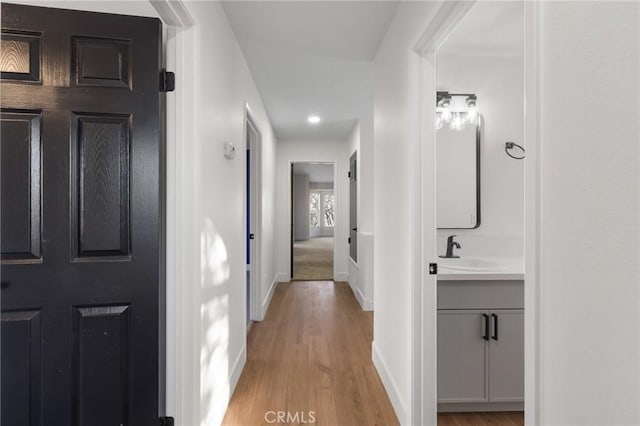 hallway featuring sink and light hardwood / wood-style floors