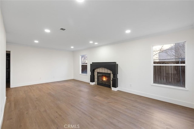 unfurnished living room featuring a fireplace, ornamental molding, and hardwood / wood-style floors