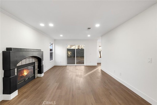 unfurnished living room featuring a fireplace, crown molding, and hardwood / wood-style floors