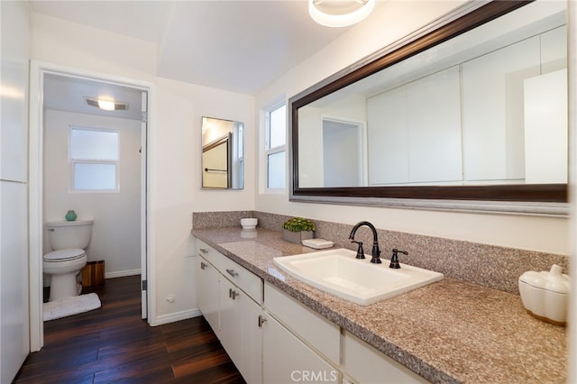 bathroom featuring toilet, hardwood / wood-style flooring, a healthy amount of sunlight, and vanity