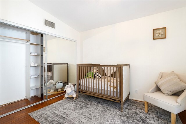 bedroom featuring a nursery area, vaulted ceiling, and wood-type flooring