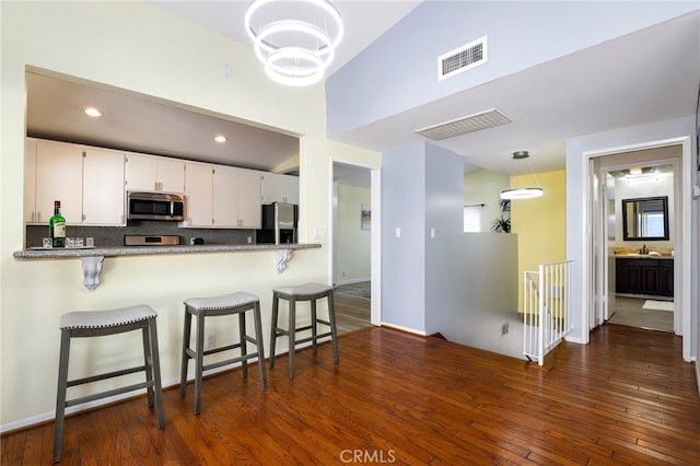 kitchen with decorative light fixtures, white cabinets, kitchen peninsula, and stainless steel appliances