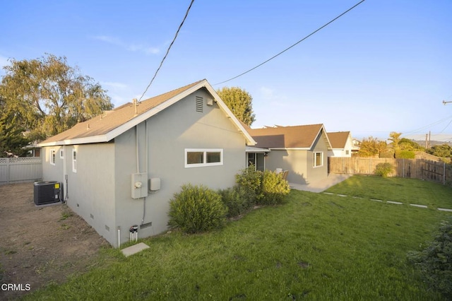 rear view of property with central AC unit and a yard