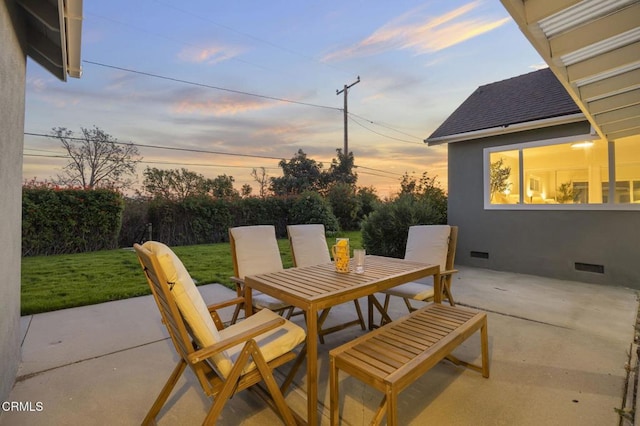 patio terrace at dusk featuring a lawn