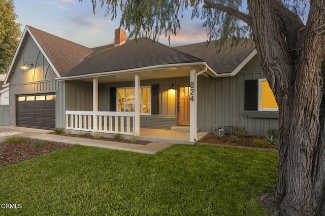 view of front of house with a yard, covered porch, and a garage