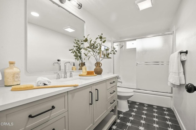 full bathroom featuring toilet, vanity, and shower / bath combination with glass door