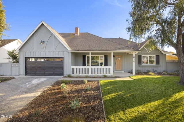 view of front of home with a front yard, covered porch, and a garage