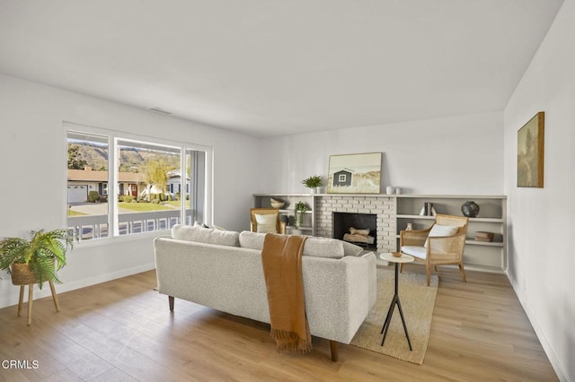 living room with a brick fireplace and light hardwood / wood-style flooring