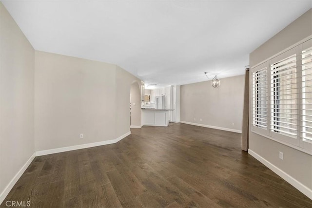 unfurnished living room with a notable chandelier and dark wood-type flooring