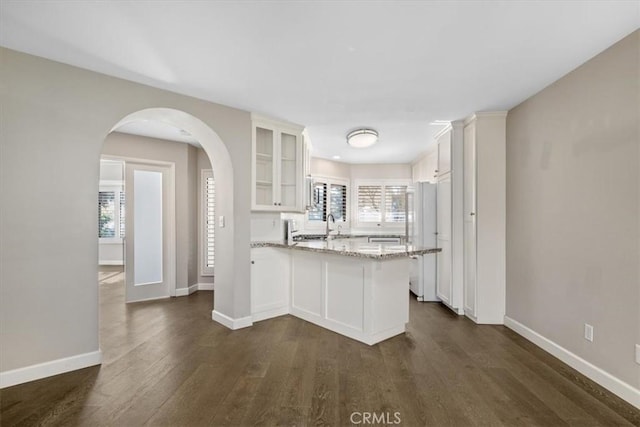 kitchen featuring a wealth of natural light, white cabinetry, light stone counters, and kitchen peninsula