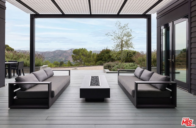 deck featuring an outdoor living space with a fire pit and a mountain view