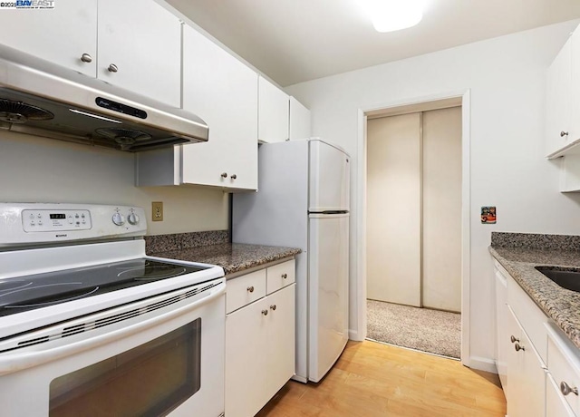 kitchen featuring white appliances, light hardwood / wood-style flooring, white cabinets, and dark stone counters