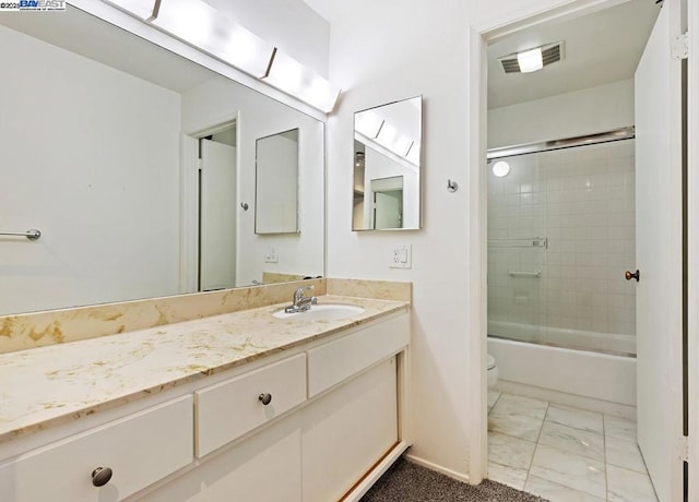 full bathroom featuring vanity, shower / bath combination with glass door, and toilet