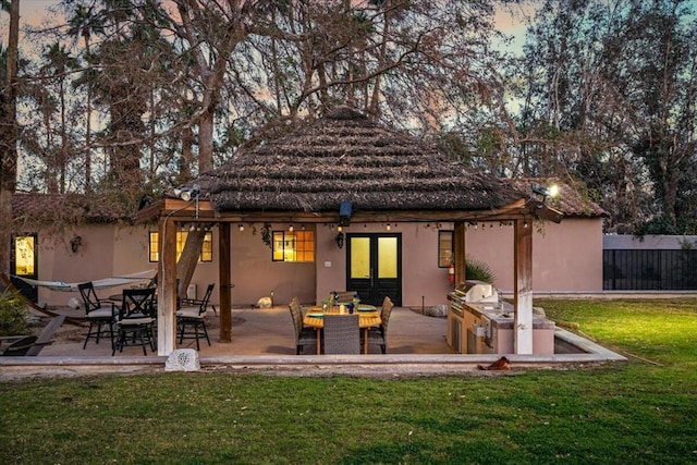 back house at dusk with a lawn and a patio area