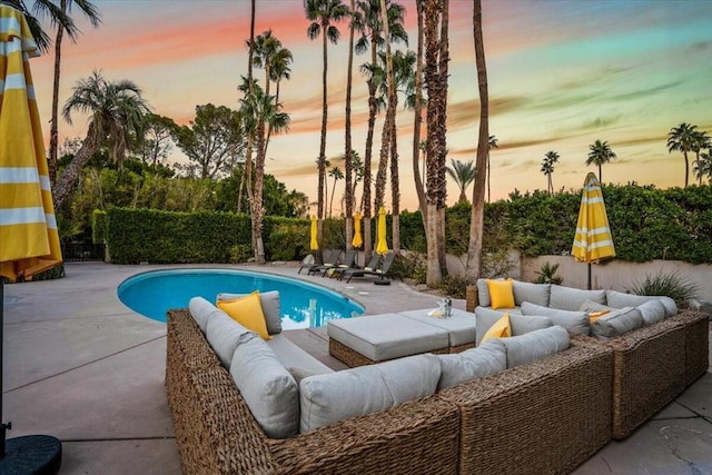 pool at dusk featuring an outdoor living space and a patio area